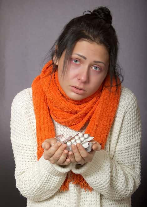 Mulher gripada com medicamentos na mão